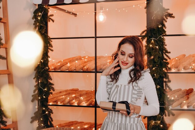 Photo a beautiful woman in a striped apron sits in a cafe christmas and new year