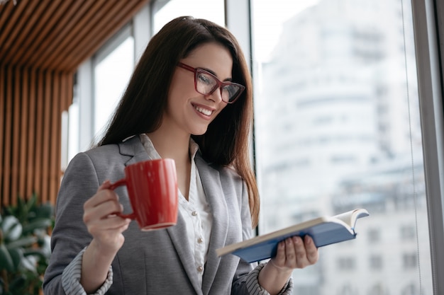 Beautiful woman in stylish eyeglasses reading book