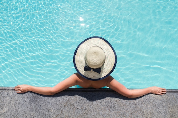 Beautiful woman sunbathing by the pool top view. Summertime.