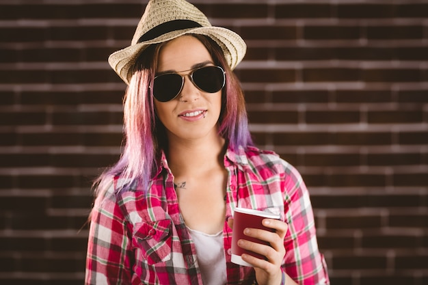 コーヒーカップを保持しているサングラスで美しい女性