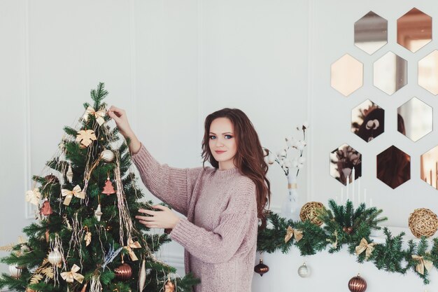 Beautiful woman in sweater decorate Christmas tree