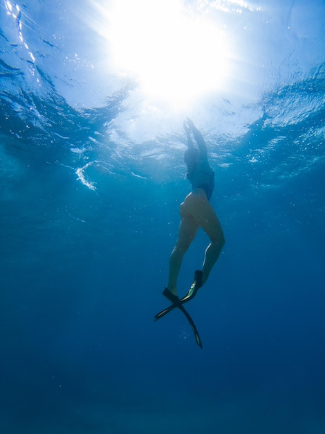 Bella donna che nuota sott'acqua con maschera per lo snorkeling e pinne