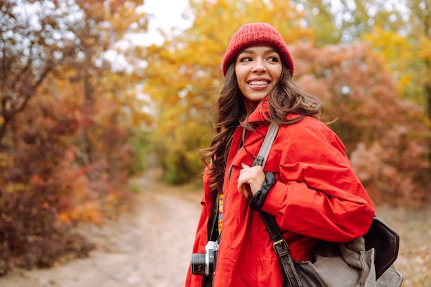 가 숲에서 사진을 찍는 아름 다운 여자 가을 날씨를 즐기는 웃는 여자
