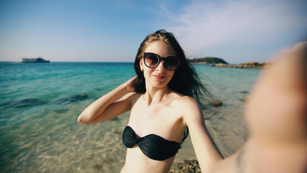 Beautiful woman taking selfie using phone on beach smiling and enjoying traveling