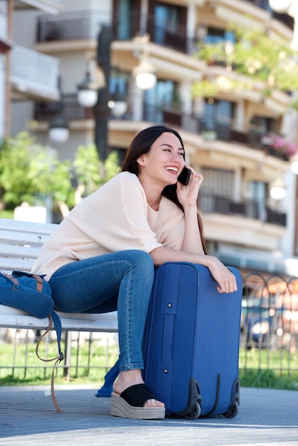 beautiful woman talking on phone outside with luggage