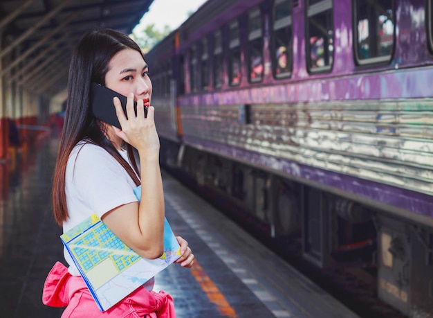 Foto bella donna parla al telefono mentre si aspetta il treno alla stazione ferroviaria.