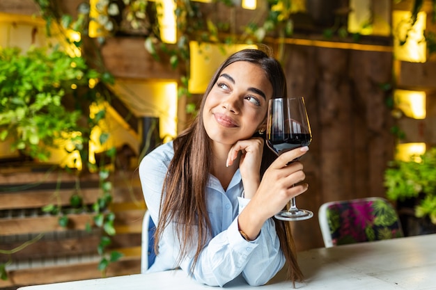 Beautiful woman tasting wine while sitting in restaurant