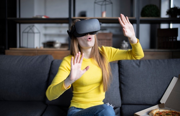 Photo beautiful woman touching air during the vr experience. girl eats pizza