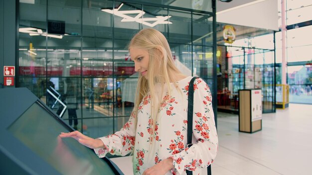 Фото Красивая женщина касается цифрового экрана, стоя в торговом центре