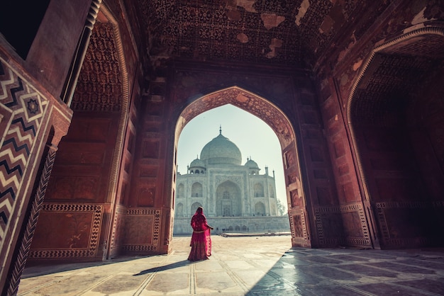 Красивая женщина в традиционном наряде, азиатская женщина, носящая типичную индийскую культуру одежды сари / сари. Taj Mahal Scenic Утренний вид памятника Тадж-Махал в Агре, Индия.