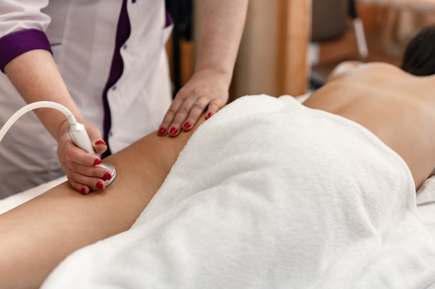 Beautiful woman undergoing procedure of anti-cellulite massage in beauty salon.