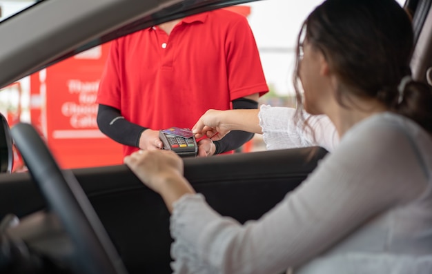 Фото Красивая женщина с помощью кредитной карты с терминалом оплаты карты для оплаты заправки бензина на азс