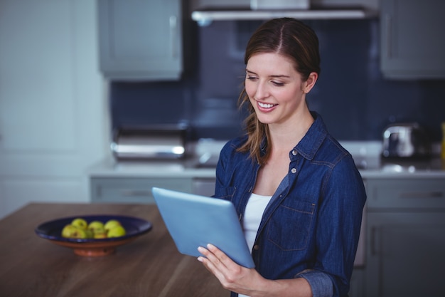 Beautiful woman using digital tablet in kitchen