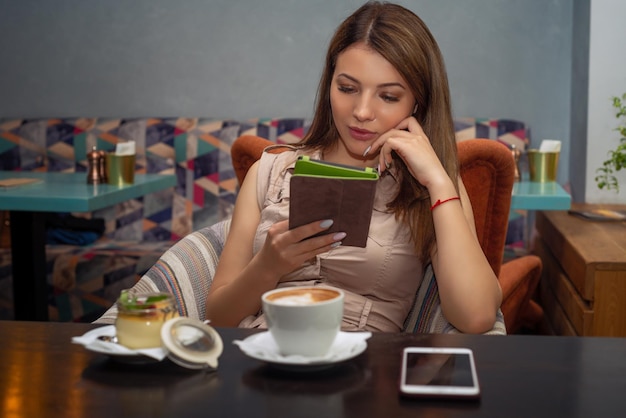 Beautiful woman using a mobile phone in cafe reading ebook