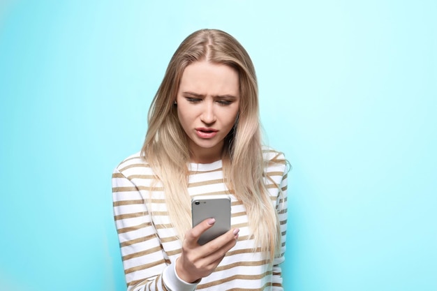 Beautiful woman using mobile phone on color background