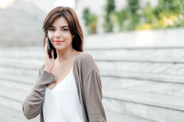 Beautiful woman using phone outdoors in the city park