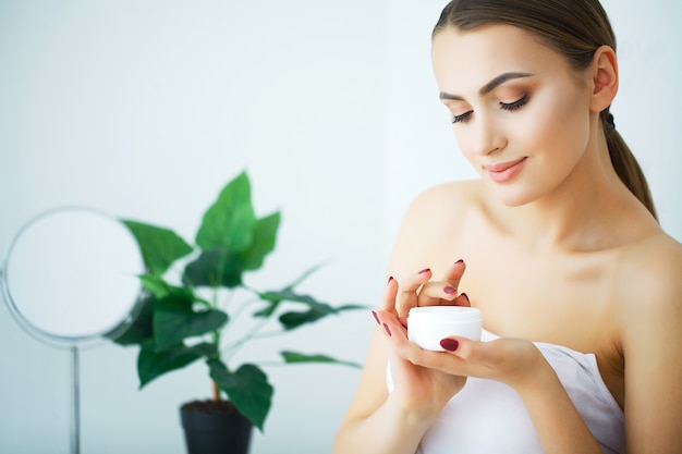 A beautiful woman using a skin care product, moisturizer or lotion and Skincare taking care of her dry complexion. Moisturizing cream in female hands