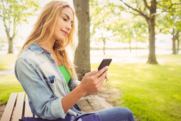 Bella donna che utilizza smartphone al parco