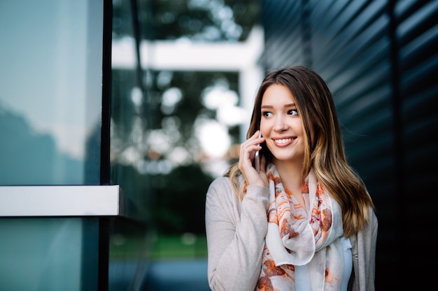 Bella donna che utilizza uno smartphone per strada. social network, tecnologia, concetto di vita frenetica