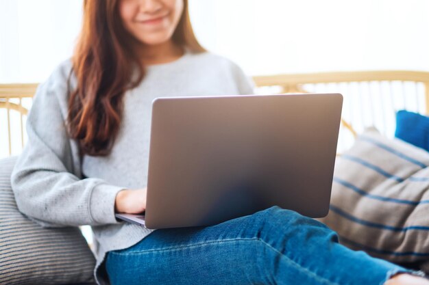 A beautiful woman using and working on laptop computer while lying on a sofa at home