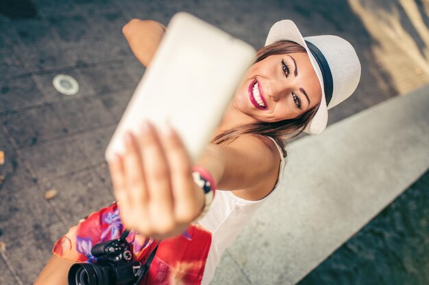 Beautiful woman on vacation taking selfie with her smart phone.