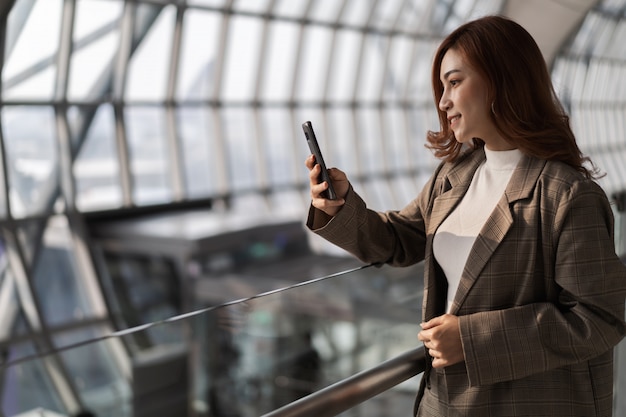 Volo aspettante della bella donna e smart phone usando nell'aeroporto