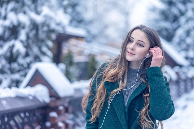 beautiful woman walks through a winter park with headphones