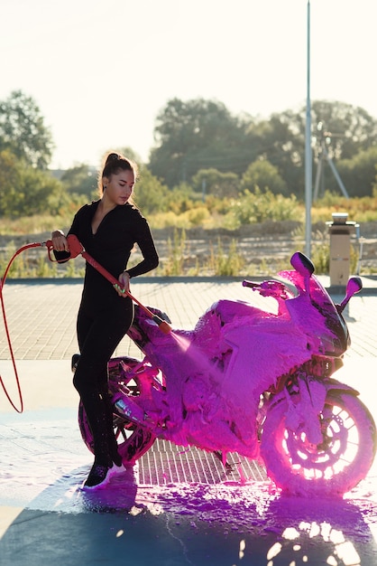 Beautiful woman washing a motorcycle