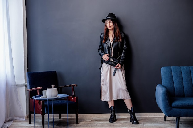 Beautiful woman wearing a beige dress, massive boots, hat, stylish fashionable appearance.