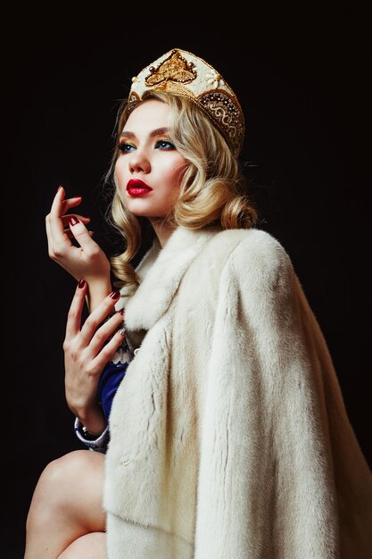 Photo beautiful woman wearing fur jacket and crown against black background