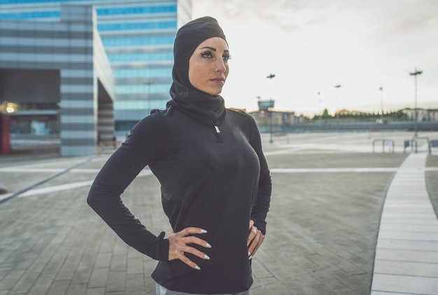 写真 ヒジャブを着た美しい女性が日の出時に建物に立っています