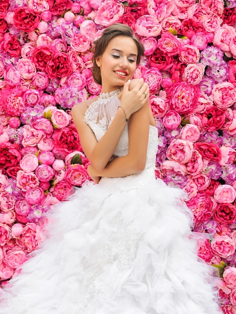 Beautiful woman in a wedding dress on a floral wall