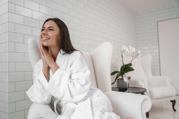 Beautiful woman in white bathrobe during medical procedure in beauty clinic