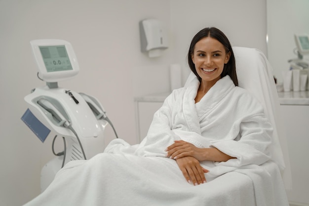 Beautiful woman in white bathrobe during medical procedure in beauty clinic