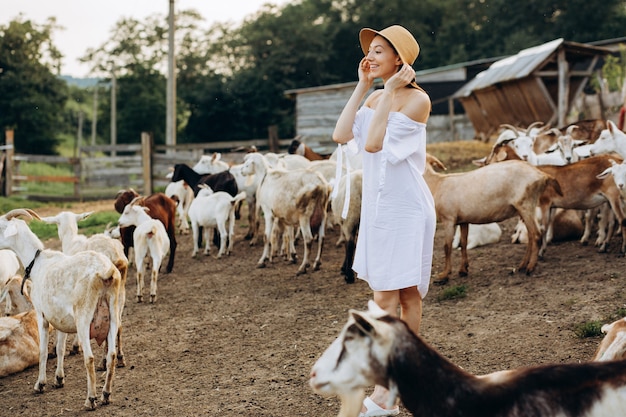 아름다운 여자와 흰 드레스와 에코 농장에서 염소 중 베이지 색 모자