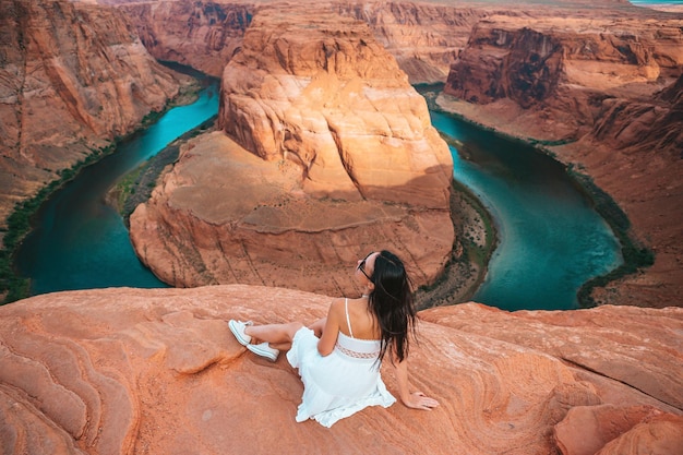 Beautiful woman in white dress on the edge of the cliff Horseshoe Band Canyon in Paje Arizona Adventure and tourism concept