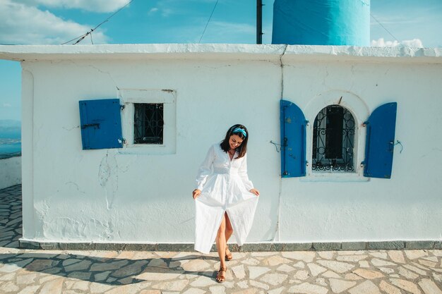 Beautiful woman in white dress near old greece church