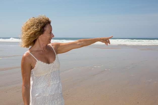 Beautiful woman in white dress pointing with an extended arm