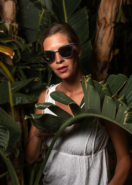 Beautiful woman in a white dress posing on the leaves backdrop