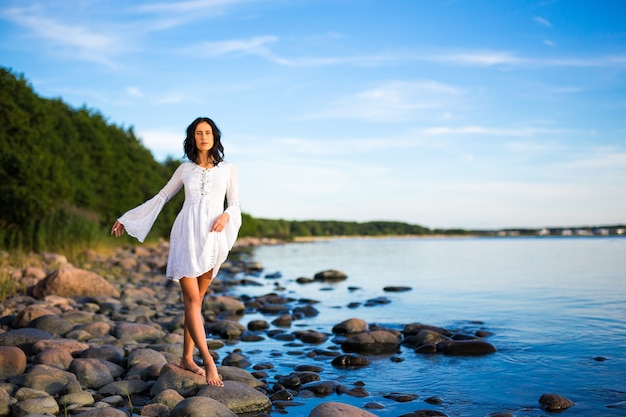 Beautiful woman in white dress walking on the beach