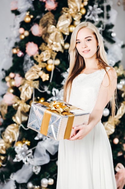 Beautiful woman in a white dress with a gift box