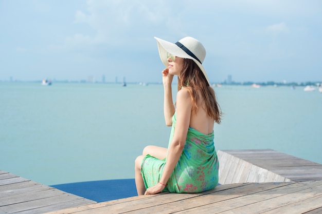 흰 모자에 아름 다운 여자는 해변 호텔에 앉아있다
