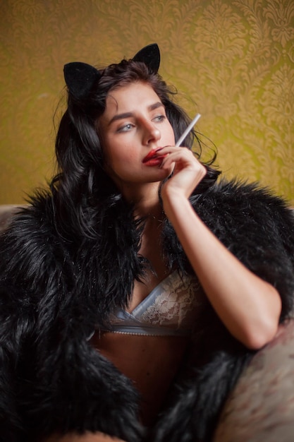 Foto bella donna in lingerie bianca e un cappotto nero con capelli neri ricci in posa in interni vintage