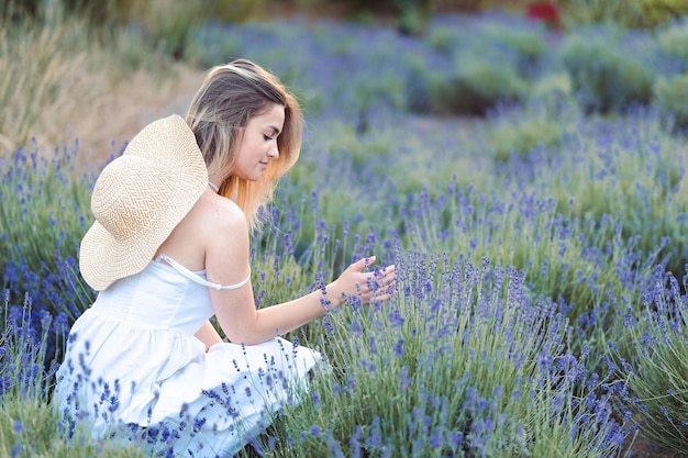 Beautiful Woman in White Sundress and Hat is Sitting in Lavender Meadow Calming Lavender Scent