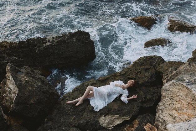 Beautiful woman in white wedding dress on sea shore wet hair\
nature landscape