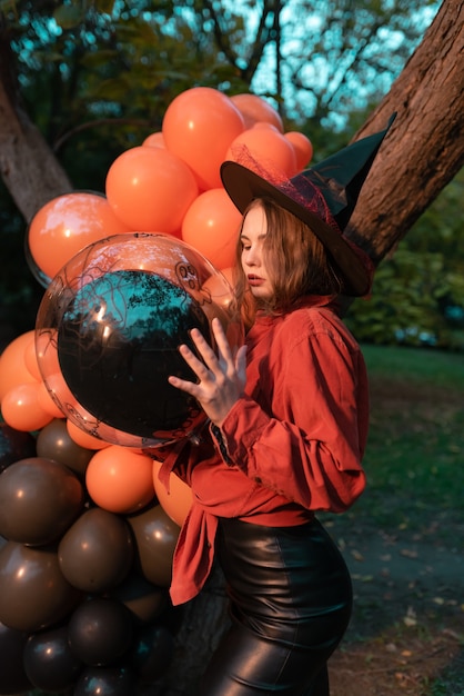 Beautiful woman in a witch costume with balloons for Halloween. Halloween decoration concept