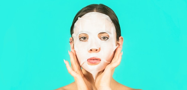 Beautiful woman with beauty mask Skin care and beauty concept Moisturizing mask Anti aging procedure Woman applying sheet mask on her face on blue background