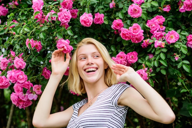 Bella donna con capelli biondi in giardino estate e parco primaverile natura rosa profumo di fiori parfume bellezza naturale spa e cura della pelle ragazza sexy su sfondo rosa rosa stagione felice