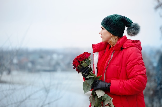 彼女の手に赤いバラの花束を持つ美しい女性