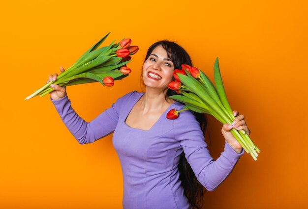 Beautiful woman with a bouquet of spring tulips on a yellow background March 8 womens day